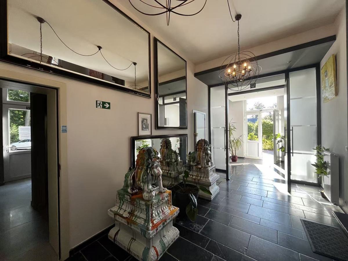 The entrance hall, with a black slate floor, an orb chandelier, tall mirrors and two large glazed ceramic Chinese guardian lions on plinths beside the doorway to reception.